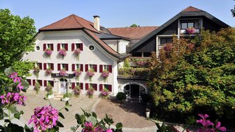 weises Haus mit roten Fensterläden und Blumen beim den Fenstern | © Tourismusverband Bergheim