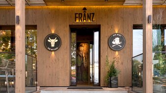 Holz verkleidete Aussenansicht mit Logo  | © Franz