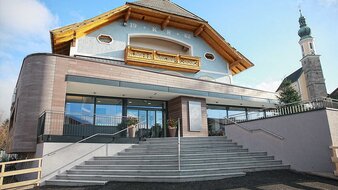 Aussenansicht mit Steintreppe, links im Hintergrund Kirche | © Rößlhuber