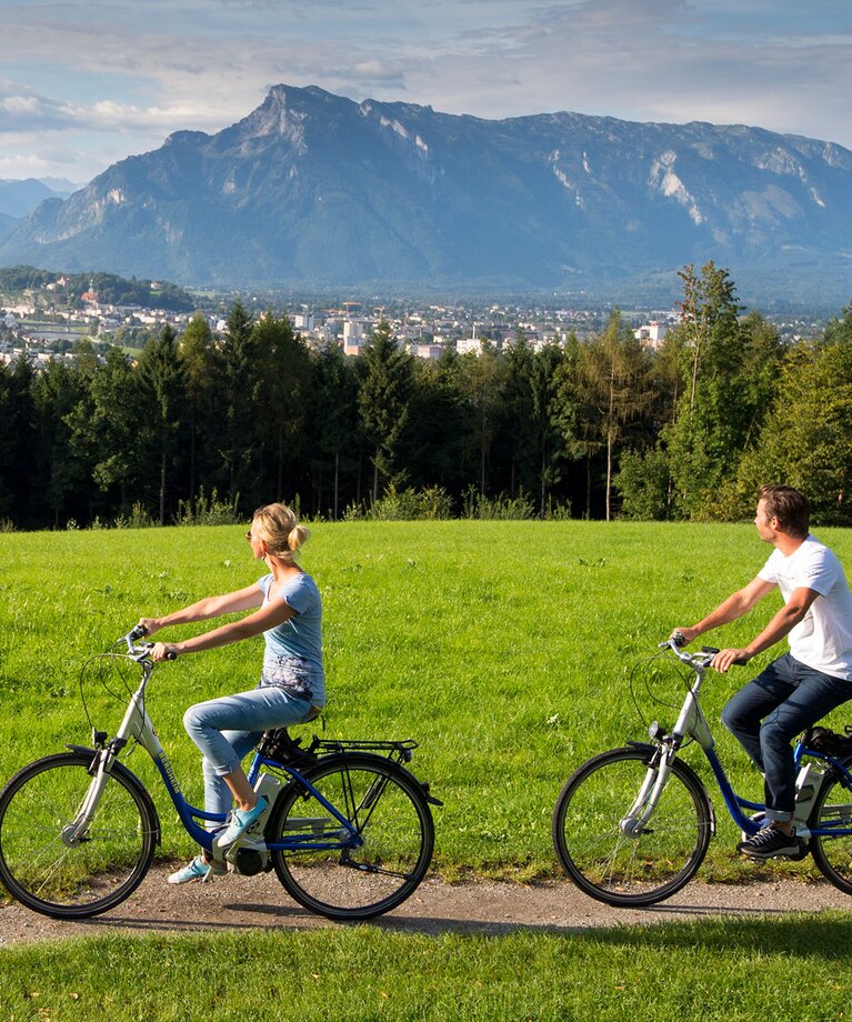 2 Radfahrer blicken auf Stadt Salzburg | © TVB Bergheim - Bryan Reinhart
