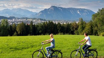2 Radfahrer blicken auf Stadt Salzburg | © TVB Bergheim - Bryan Reinhart