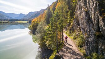 Radfahrer fährt auf einen Schotterweg entlang eines Sees | © SalzburgerLand Tourismus/Christoph Oberschneider