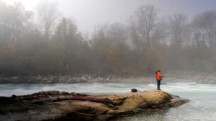 Mann steht auf Felsen und fischt in einem Fluss | © Tourismusverband Bergheim/Simon Krieg