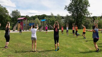 Gruppe von Menschen stehen im Kreis und turnen | © Tourismusverband Bergheim/Herbert Podlipnik