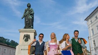 Mozartstatue und davor 2 Frauen und 2 Männer in Tracht | © Tourismus Salzburg/Bryan Reinhart
