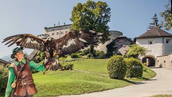 Falknerin mit Greifvogel am Arm, im Hintergrund Burg | © SalzburgerLand Tourismus