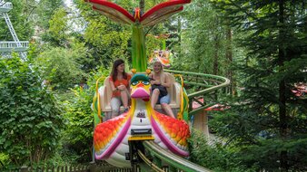 2 Mädchen fahren in einem kleinen Wagen in Form einer Schnecke auf einer erhöhten Schiene | © FANTASIANA Straßwalchen