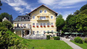 Gelbes Haus mit weißen Fenstern und Blumen, Gastgarten mit Kastanienbäumen | © Hotel Gasthof Maria Plain