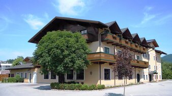 Hellbraunes Haus mit Balkonen und Baum davor | © Jägerwirt