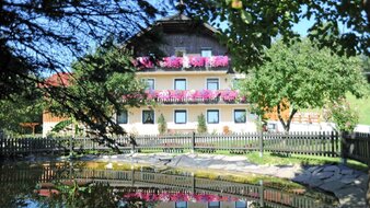 Gelbes Bauernhaus mit üppig blühenden Balkonblumen | © Haus Monika