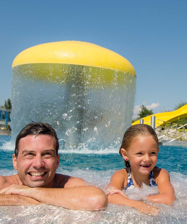 Zwei Erwachsene und ein Kind lehnen am Rand des Schwimmbeckens | © Tourismusverband Bergheim/Bryan Reinhart